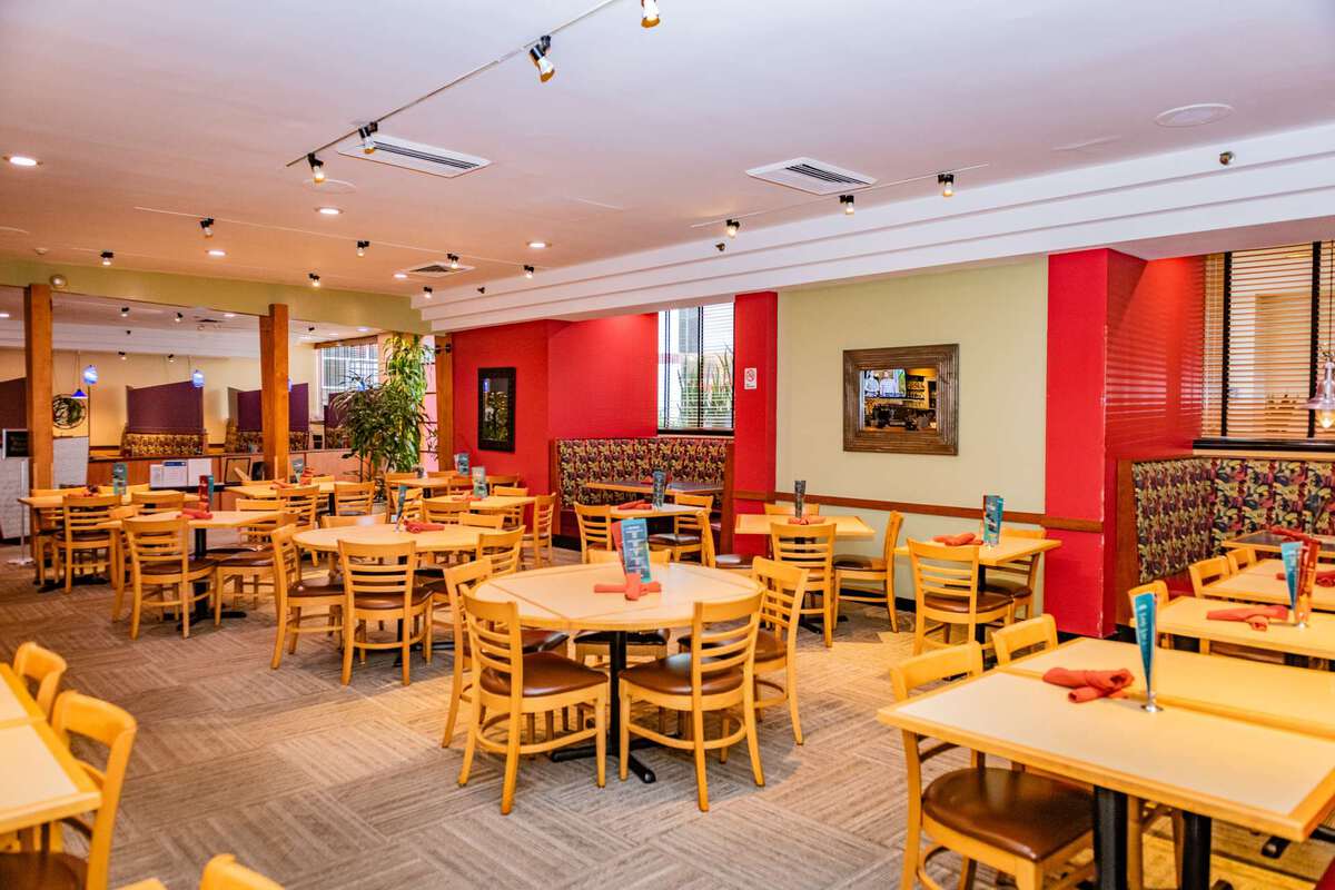 A dining area with round and rectangular tables, wooden chairs, booths, and menus.