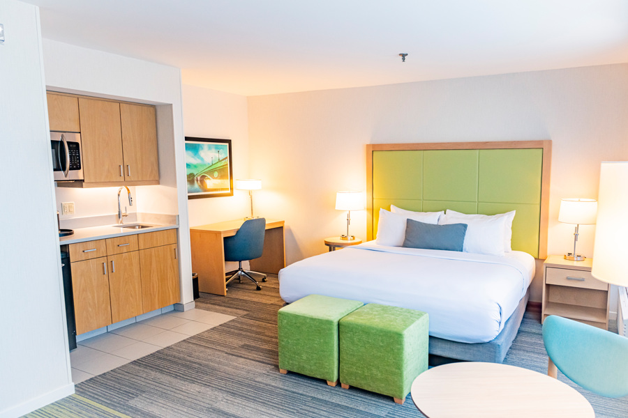 A hotel suite with a kitchenette, desk, and bed