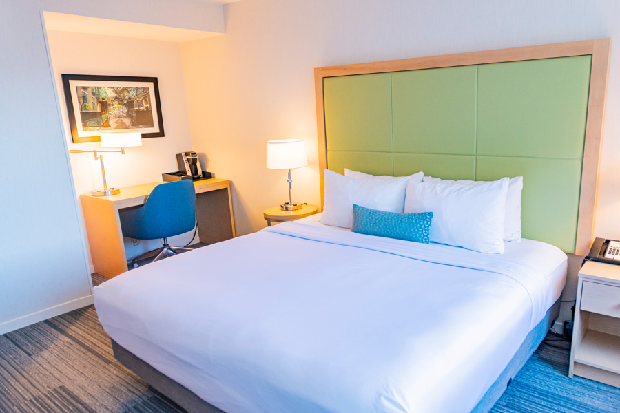 A hotel room with a large bed, desk, and chair.