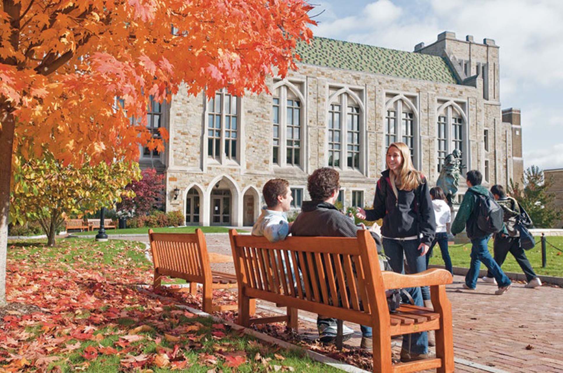 Students sitting on a bench on campus during fall