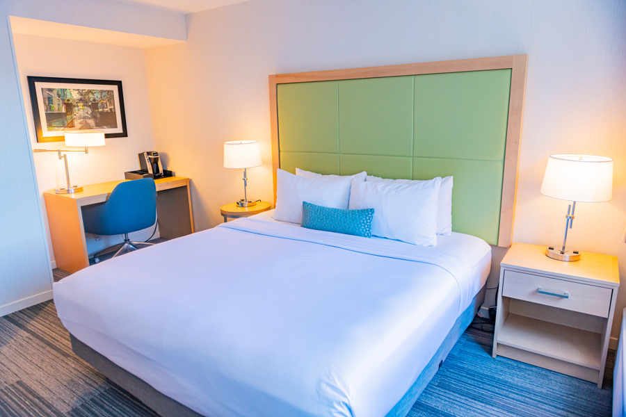 A hotel room with a large bed, desk, and nightstands.