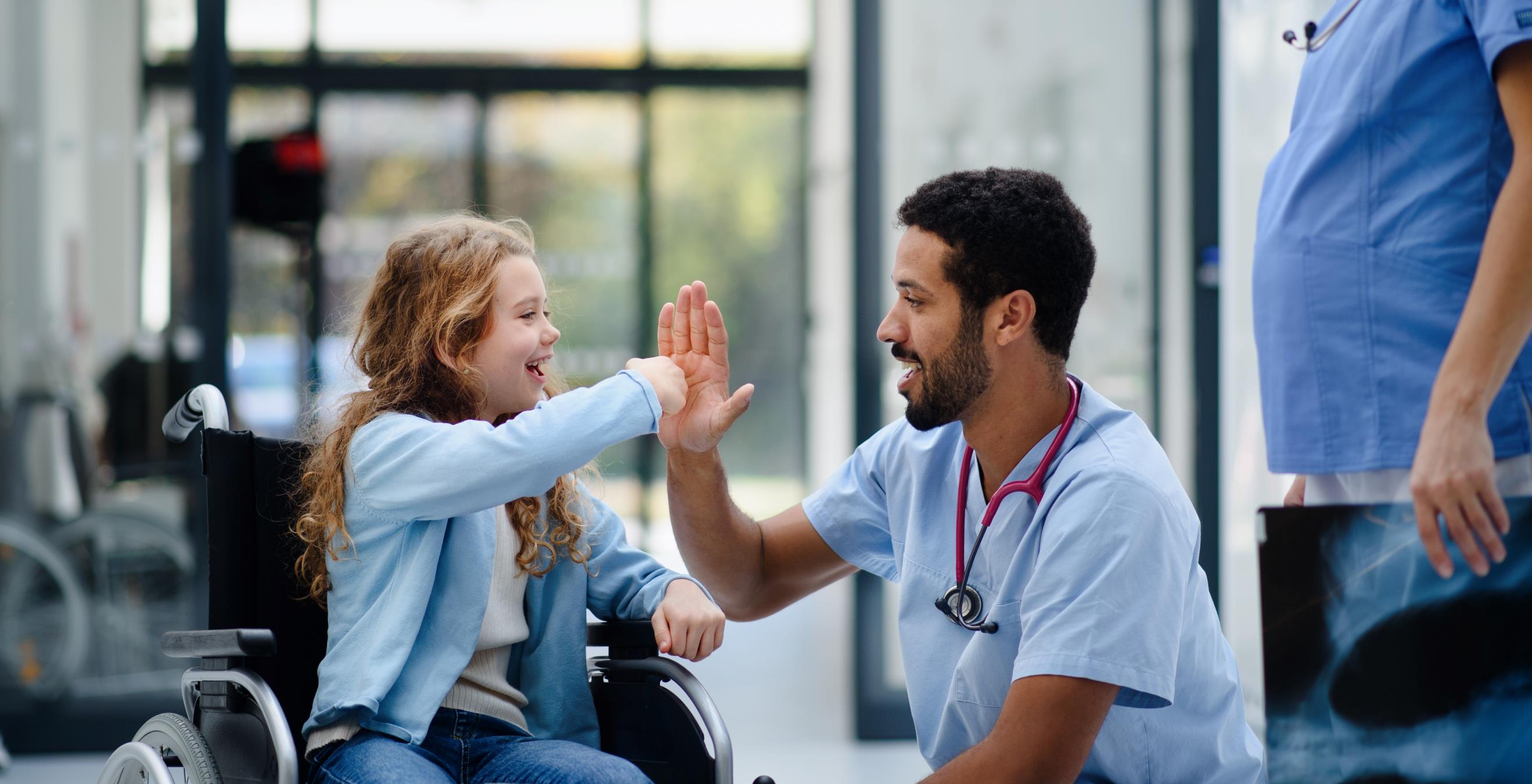 Child in wheelchair high fiving doctor 